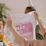 Mãe e filha sorrindo e se abraçando em um dia ensolarado, com balões de festa ao fundo