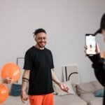 Duas amigas rindo e celebrando um aniversário com balões e confetes, tirando uma selfie para redes sociais.