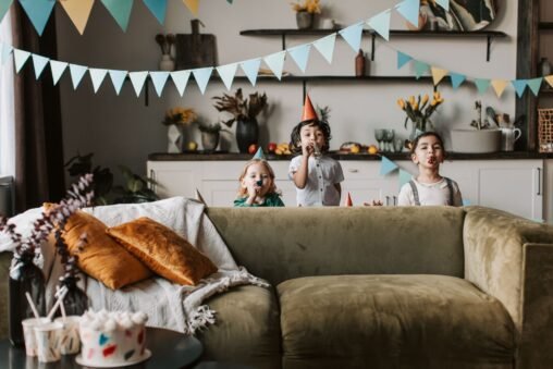 Mãos de criança segurando um convite de aniversário colorido com balões e confetes