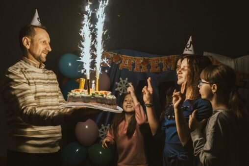 Pai ou mãe abraçando a filha em seu aniversário, com balões e um celular exibindo um status do WhatsApp